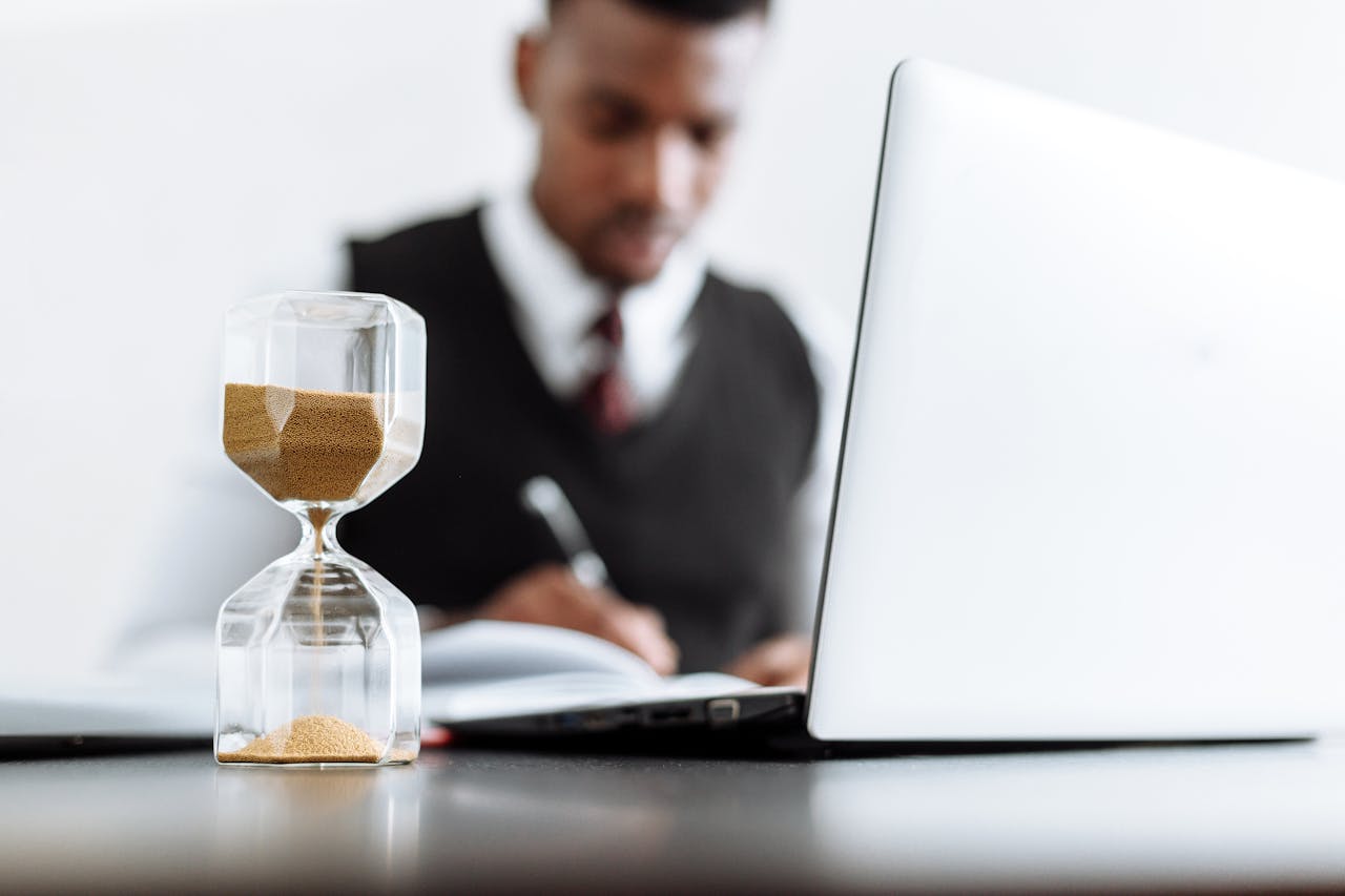 hero-contact Businessman at desk with hourglass indicating time management and daily work routine.